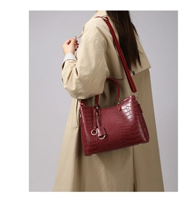 Side view of elegant burgundy crocodile pattern tote bag styled with a beige trench coat