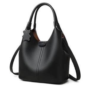 Elegante borsa a secchiello in pelle nera con doppi manici e ciondolo a orsetto