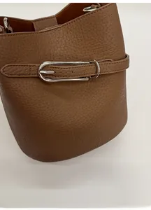 Gros plan détaillé d'un sac seau en cuir litchi marron avec boucle en métal argenté