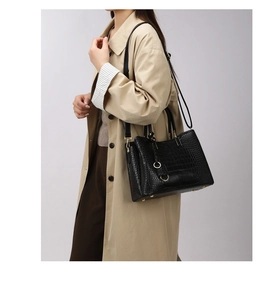 Close-up of black crocodile pattern tote bag with gold hardware on a trench coat model