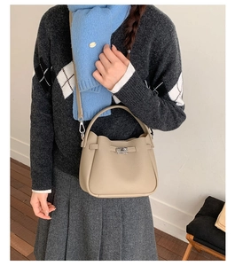 Détail d'un sac seau en cuir kaki avec fermoir tournant argenté porté par un mannequin