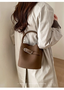 Détail du sac seau en cuir marron avec motif litchi et boucle métallique dorée