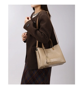 Detail view of beige crocodile embossed tote bag featuring elegant ring handles and strap