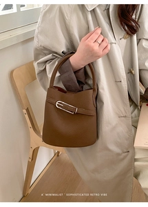 Détail d'un sac seau marron foncé en cuir grainé avec sangle décorative et boucle argent
