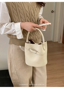 Détail du sac seau rétro en cuir crème montrant le grain de cuir et la boucle métallique