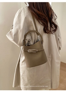 Détails du sac seau marron à motif litchi sur mannequin avec un style rétro minimaliste