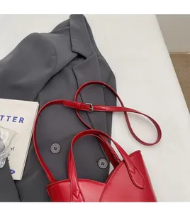 Detail view of red leather bucket bag with silver metal buckles and adjustable strap