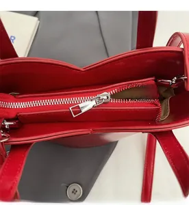 Close-up of the smooth silver metal zipper and red leather interior of the bucket bag