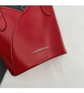 Close-up of bright red bucket bag featuring Fashion & Bags logo and fine stitching