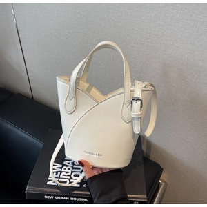 Close-up of cream leather bucket bag with artistic petal layer design and silver hardware