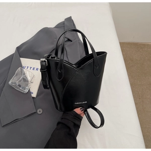 Detail of black glossy bucket bag with Fashion & Bags lettering and V-shaped top design