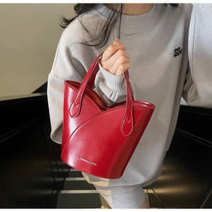 Close-up of bright red bucket bag with gloss finish and FASHION & BAGS logo detail