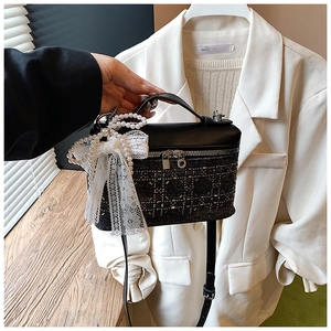 Detalle de bolso vaquero con pedrería, lazo de encaje y colgante de perlas