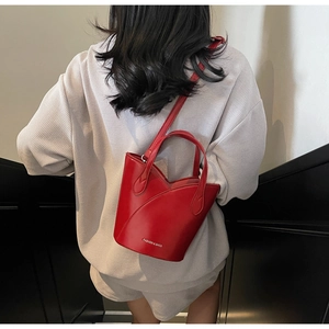 Detail of red leather bucket bag featuring arc stitching and silver decorative lettering