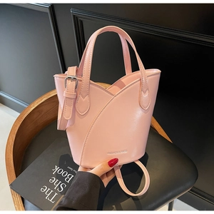 Pink petal-shaped bucket bag with adjustable strap on a minimalist armchair