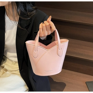 Detail shot of light pink bucket bag with tulip shape design and silver logo text