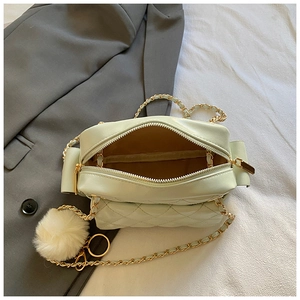 Detail of light green quilted small square bag showing chain strap and soft plush ball