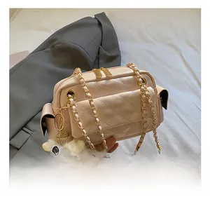 Detail of light pink quilted handbag with gold zippers and a plush yellow pompom charm