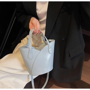 Detail of light blue bucket bag showing smooth PU leather and silver embossed logo text