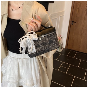 Detalle de bolso caja de tweed con colgante de perlas y lazo de encaje elegante