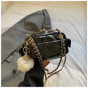 Close-up of black quilted leather crossbody bag with gold chain and plush charm