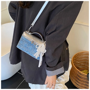 Detalle del bolso bandolera de mezclilla y cuero plateado con borla de perlas en el modelo