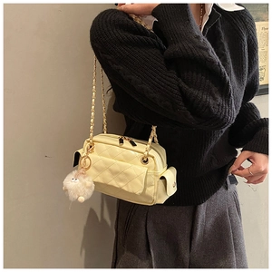 Detail of quilted leather crossbody bag in pale yellow with a plush sheep charm