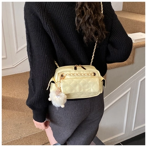 Detail of yellow quilted crossbody bag with a cute white lamb plush keychain charm