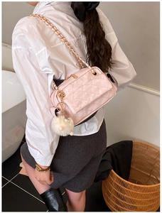 Detailed view of pink quilted crossbody bag with gold chain and white fur ball charm