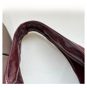 Detailansicht des bequemen Ledergriffs mit glänzender Textur an dunkelroter Tasche