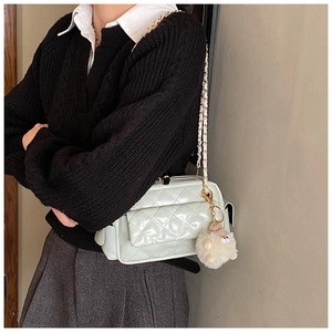 Side view of mint green quilted leather bag with gold chain and white plush charm detail