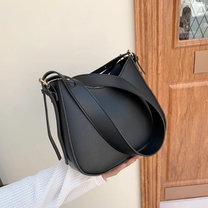 Minimalist black leather shoulder bag with gold hardware and wide strap for women