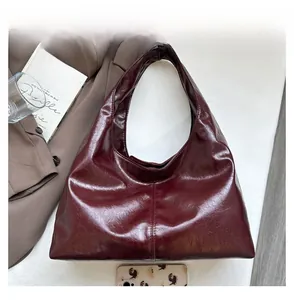Detailaufnahme der bordeauxroten Lackleder-Tasche mit Handy zum Größenvergleich