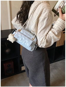 Quilted light blue leather crossbody bag with gold chain strap and plush pompom detail