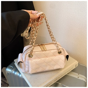 Close-up of light pink quilted crossbody bag with gold chain strap and dual zippers