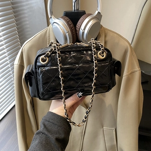 Close-up of black quilted camera bag featuring gold chain strap and dual zipper detail