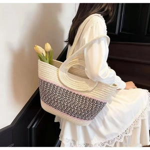 Detail of woven straw tote bag with pattern and flowers on a white lace dress backdrop