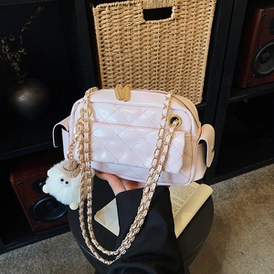 Detail of pink quilted patent leather bag with gold chain strap and plush charm