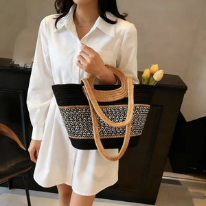 Detail of woven straw tote bag with black geometric patterns and dual shoulder straps