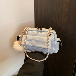 Close-up of light blue quilted leather handbag with gold chain strap and plush charm