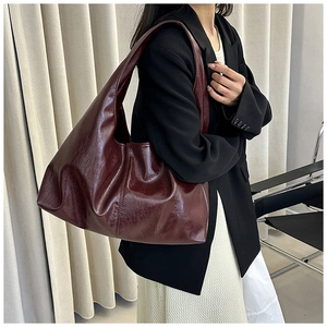 Detailansicht einer großen burgunderroten Tote-Bag aus Öl-Wachs-Leder an einem Model