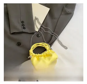 Detail of a bright yellow mini PU bag featuring a pleated design and silver chain strap