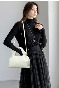 Sac nuage chic en cuir crème avec poignée et bandoulière porté par un mannequin en noir