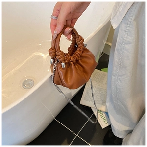 Detail of a brown ruched cloud mini bag with silver chain strap and round handle