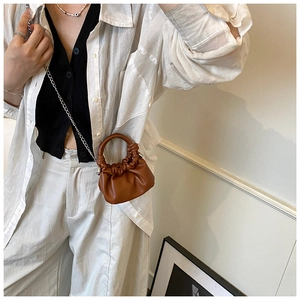 Detail of a brown pleated cloud bag with a circular handle and silver chain strap