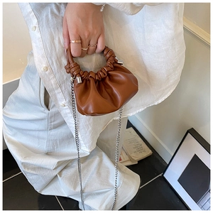 Detail of brown pleated cloud bag with metallic handle and silver chain strap