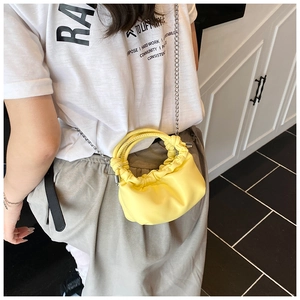Side view of a pale yellow ruched PU leather cloud bag with a silver chain and ring handle