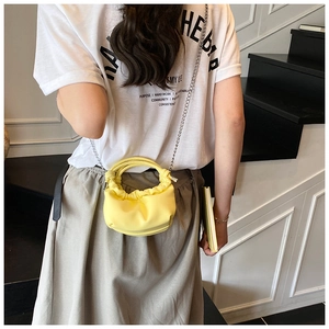 Yellow pleated cloud mini bag with silver chain strap shown worn on the shoulder
