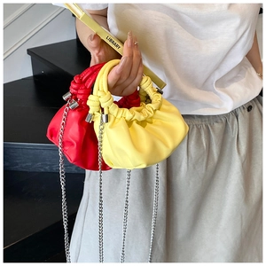 Close-up of vibrant yellow and red pleated cloud bags with elegant silver chain straps