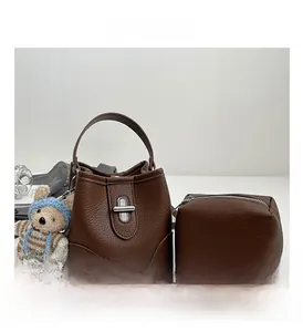 Macro shot of dark brown litchi pattern leather bucket bag with silver turn-lock and bear charm